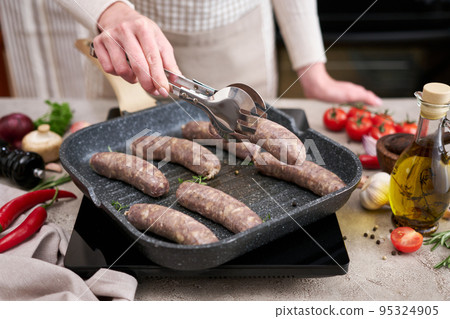 Grilled sausages on a grill frying pan on a domestic kitchen 95324905