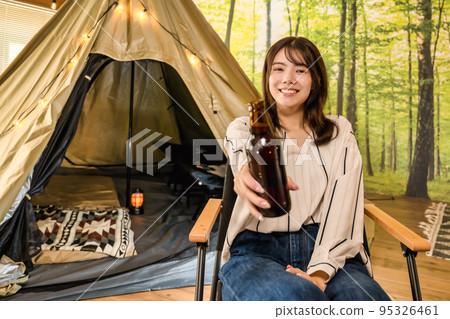 Young woman smiling with beer in camp 95326461