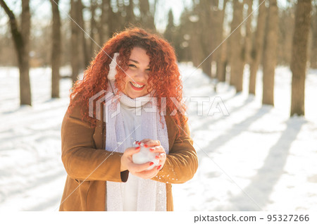 Fat caucasian woman playing snowballs in the park.  95327266