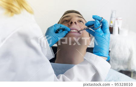 Installation of braces, bridges and a dental plate to correct teeth. An orthodontist installs a bracket system on an uneven jaw. Implants and smile correction. Concept of working in the dentist office Installation of braces, bridges and a dental plate to correct teeth. An orthodontist installs a bracket system on an uneven jaw. Implants and smile correction. Concept of working in the dentist office 95328010