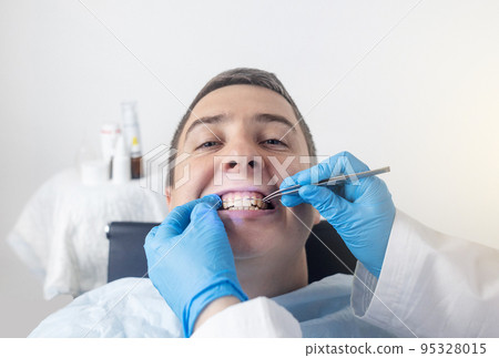 Installation of braces, bridges and a dental plate to correct teeth. An orthodontist installs a bracket system on an uneven jaw. Implants and smile correction. Concept of working in the dentist office 95328015