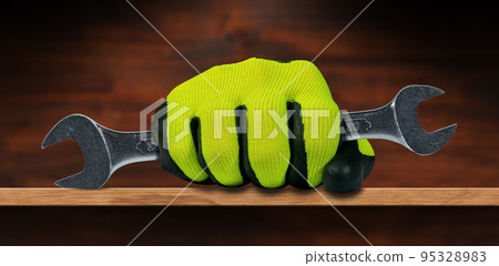 Hand with Protective Work Glove Holding a Steel Wrench 95328983
