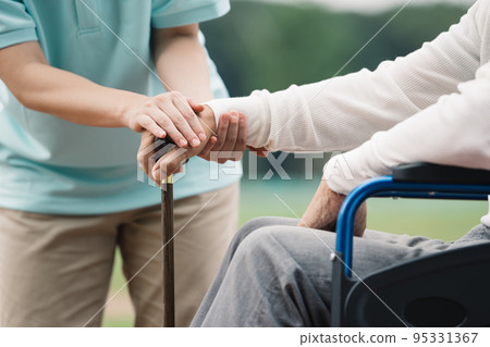 一個坐在輪椅上的男人和一個幫助走路的看護人 95331367