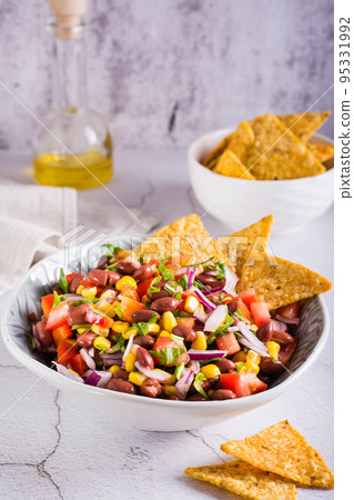 Mexican vegetable salad cowboy caviar and nachos in a bowl on the table. Vertical view Mexican vegetable salad cowboy caviar and nachos in a bowl on the table. Vertical view 95331992