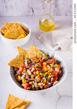 Homemade cowboy caviar traditional mexican vegetable salad and nachos in a bowl. Vertical view Homemade cowboy caviar traditional mexican vegetable salad and nachos in a bowl. Vertical view 95331994