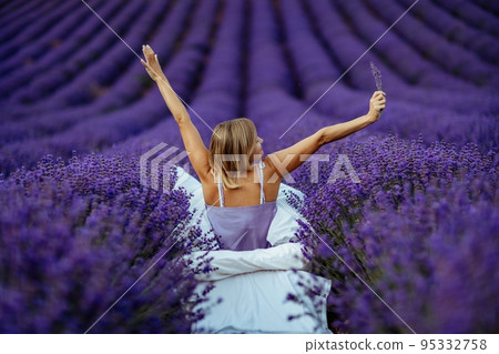 A middle-aged woman sits in a lavender field and enjoys aromatherapy. Aromatherapy concept, lavender oil, photo session in lavender A middle-aged woman sits in a lavender field and enjoys aromatherapy. Aromatherapy concept, lavender oil, photo session in lavender 95332758