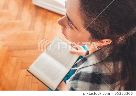 A student reads a book. View from the top, over the head. Concept of reading and learning 95333306
