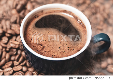 A cup of coffee and coffee beans on a black background, an aromatic and energy drink. 95333993