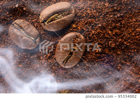 top view of coffee beans and ground coffee steaming with heat. top view of coffee beans and ground coffee steaming with heat. 95334002