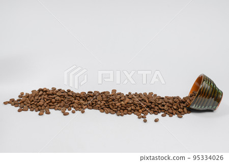 Path of coffee beans spilled from a mug, coffee on an isolated white background. Path of coffee beans spilled from a mug, coffee on an isolated white background. 95334026