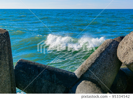 Wave breaker along the sea shore on the sand beach. 95334542