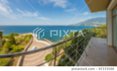 Abstract defocused sea view with clear blur sky, view from high floor of luxury hotel apartment room terrace. Blurred background view from the balcony to the sea on sunny day. City near the sea. 95335086