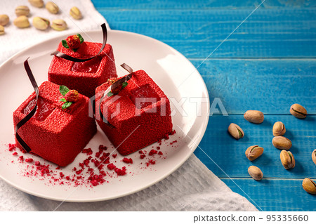 Red cube-shaped cakes with pistachio biscuit, chocolate souffle, raspberry confit and nut crumbs Red cube-shaped cakes with pistachio biscuit, chocolate souffle, raspberry confit and nut crumbs 95335660