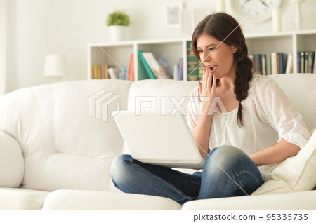 Portrait of a beautiful woman with laptop on the sofa 95335735