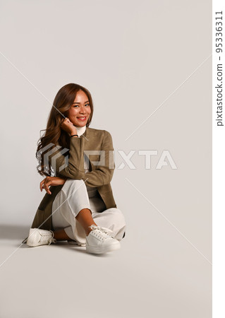 Portrait of beautiful young woman in stylish jacket sitting on white background. Autumn fashion concept Portrait of beautiful young woman in stylish jacket sitting on white background. Autumn fashion concept 95336311