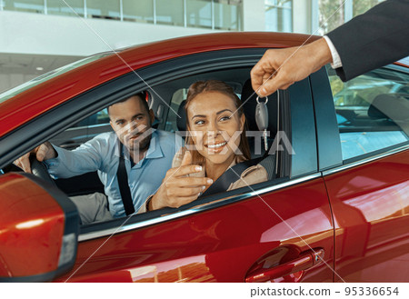 Young couple sitting inside new car and holding keys to it. Concept for car rental 95336654