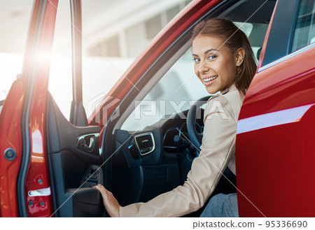 Young smiling woman sitting inside her new car. Concept for car rental 95336690