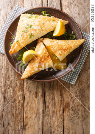 Brik Tunisian savory filo dough pastry stuffed with tuna, vegetables and egg close-up in a plate. vertical top view Brik Tunisian savory filo dough pastry stuffed with tuna, vegetables and egg close-up in a plate. vertical top view 95336858