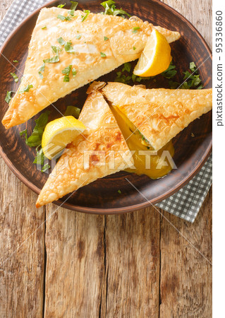 Tunisian brik is a popular dish that incorporates flaky dough filled with a variety of savory ingredients close up in the plate. Vertical top view Tunisian brik is a popular dish that incorporates flaky dough filled with a variety of savory ingredients close up in the plate. Vertical top view 95336860