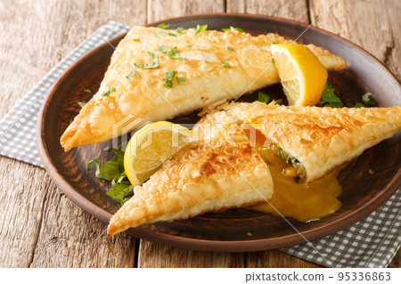 Brik is a very thin, brittle pastry used in Tunisian cooking is the base for a breakfast pastry stuffed with egg, potato, tuna fish close up in the plate. Horizontal 95336863