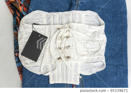 White top with lacing and empty black label. Branding mock up. Corset on jeans background, back side 95339671