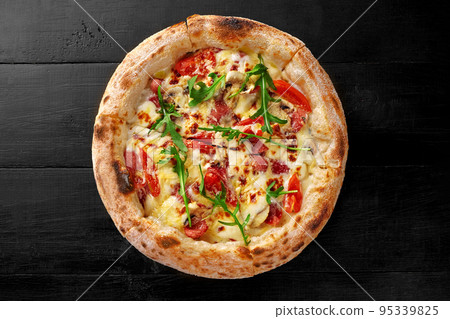 Boscaiola pizza with cream, mozzarella, cabanossi, salami, mushrooms, parmesan and fresh arugula on black wooden surface 95339825