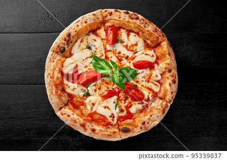 Traditional pizza Margherita with pelati sauce, mozzarella, tomatoes and basil on black wooden surface Traditional pizza Margherita with pelati sauce, mozzarella, tomatoes and basil on black wooden surface 95339837
