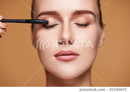 young woman applying eyeshadows on the eyelids 95340672