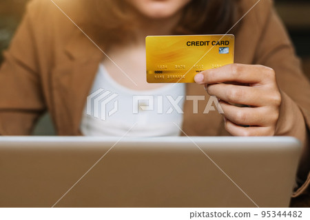 Hands holding credit card and using laptop in office home. Online shopping. Hands holding credit card and using laptop in office home. Online shopping. 95344482