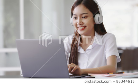 Happy Asian beautiful woman listening music with headphones while working with laptop computer. Happy Asian beautiful woman listening music with headphones while working with laptop computer. 95344615