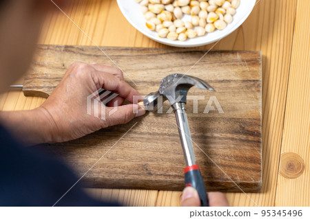 A ginkgo nut is hit with a hammer to break the shell 95345496