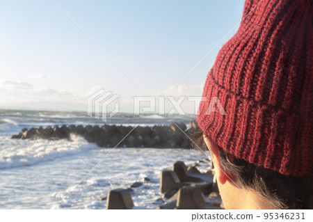The back view of a Japanese man in a knitted hat against the background of the winter sea and sky 95346231
