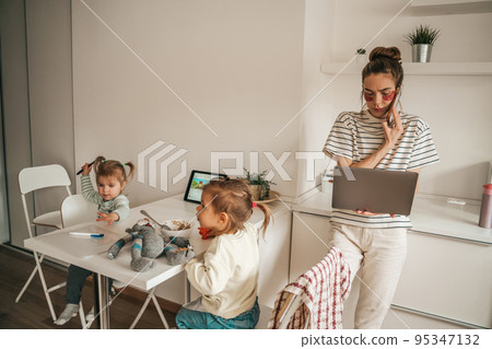 Busy female freelancer and her kids in the kitchen Busy female freelancer and her kids in the kitchen 95347132