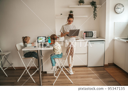 Working mom and her children in the kitchen Working mom and her children in the kitchen 95347135