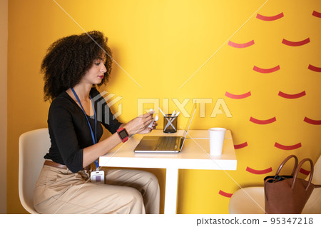 Curly-haired young woman putting on wireless earphones 95347218