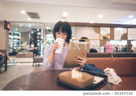 Young adult business asian woman sipping coffee and using tablet for online internet at cafe. Young adult business asian woman sipping coffee and using tablet for online internet at cafe. 95347530