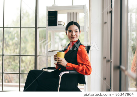 Relax business woman with coffee cup in office with window light. Relax business woman with coffee cup in office with window light. 95347904