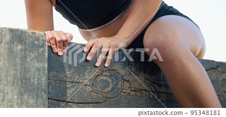 Participant in an obstacle course running and climbing a wall, jump over a wall obstacle 95348181