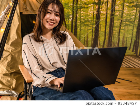 Workation A young woman working at a campsite Workation A young woman working at a campsite 95348457