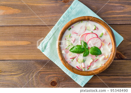 The national Russian dish is okroshka. Cold soup with vegetables and herbs on kefir. Rustic style. Top view 95348490