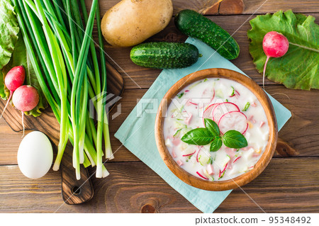 Russian kitchen. Okroshka - cold soup with vegetables and herbs on kefir. Rustic style. Top view 95348492