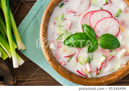 Russian kitchen. Okroshka - cold soup with vegetables, sausages and herbs on kefir. Rustic style. Close-up. Top view 95348494