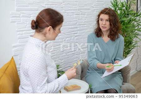 Psychologist analyzes associations on metaphorical cards in a session with a patient. Psychologist analyzes associations on metaphorical cards in a session with a patient. 95349063