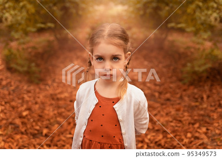 portrait of a little cute girl with pigtails among the leaves in the forest 95349573
