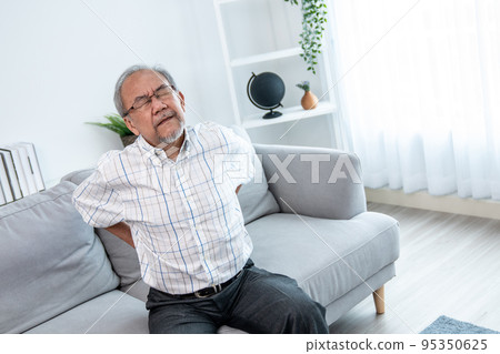 An agonizing senior man is holding his back due to back pain. An agonizing senior man is holding his back due to back pain. 95350625