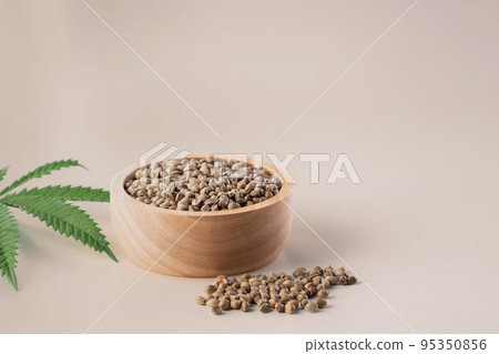 Hemp seeds with green sativa hemp leaf on top. Legalized marijuana concept. Hemp seeds with green sativa hemp leaf on top. Legalized marijuana concept. 95350856