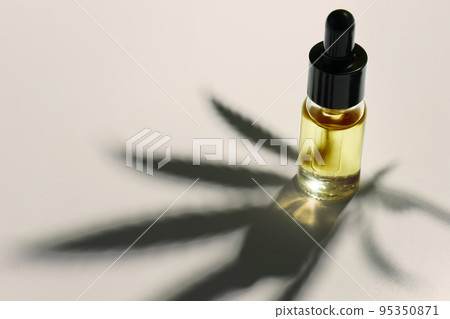 Legalized cannabis sativa hemp leaf and container of CBD oil with dropper lid. 95350871