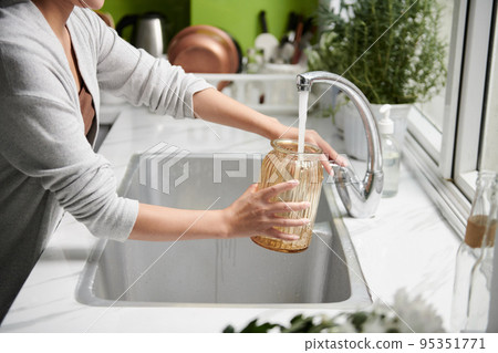 Cropped image of woman filling vase with tap water Cropped image of woman filling vase with tap water 95351771