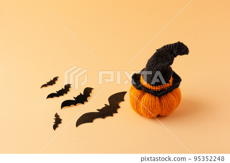 Knitted orange pumpkin with a black witch hat on an orange background, autumn composition, front view. Halloween concept. Knitted orange pumpkin with a black witch hat on an orange background, autumn composition, front view. Halloween concept. 95352248