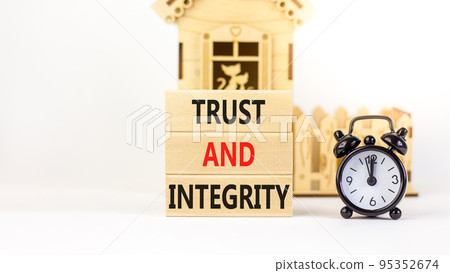 Trust and integrity symbol. Concept words Trust and integrity on wooden blocks. Black alarm clock. Beautiful white background. Business, psychological and trust and integrity concept. Copy space. 95352674
